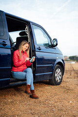 happy woman sitting in a blue van travel concept. woman using mobile phone