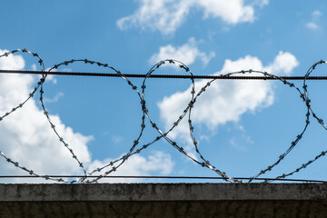 fence with barbwire against blue sky. Border or prison concept