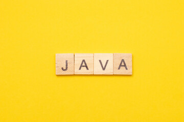 Word JAVA made from wooden letters on yellow background. Modern Programming language for software development