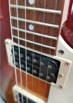 Type of strings, neck of a red and white electric guitar.