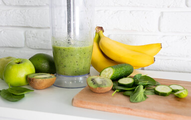 Close-up blender process. Cooking a green healthy smoothie. Mixing in a blender bowl. Making green detox smoothie. Healthy green smoothie with banana, spinach, avocado, apple and mint. Vegan food.