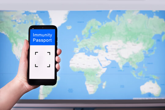 Female hand holding a cell phone with digital immunity passport on the world map background.
