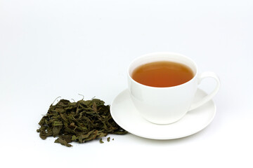 Tulsi or holy basil tea in white cup with pile of dried tulsi leaf isolated on white background. Ayurvedic medicine in India. Drink for health.