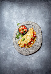 Big potato pancake with tomato sauce salsa on gray plate, gray background, top view