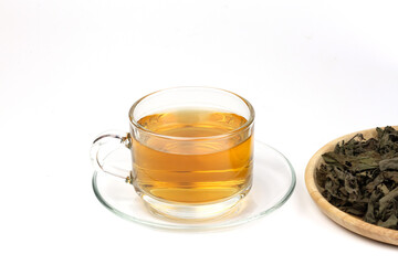 Tulsi or holy basil tea in transparent cup with dried tulsi leaf on wooden plate isolated on white background. Ayurvedic medicine in India. Drink for health.