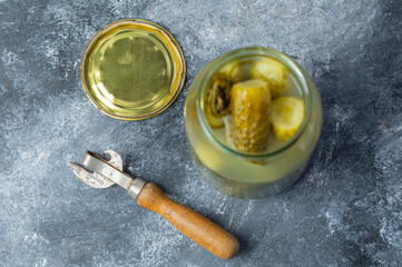 Close up photo of Opened jar full with pickled cucumber on grey background