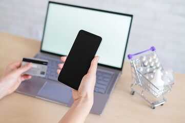 Online pharmacy concept. Woman holds credit card and smartphone. A girl makes an online purchase of medicines with home delivery using the mobile application.