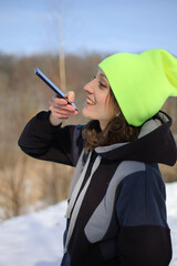 Young fitness trainer in dark sportswear and bright hat sending audio voice message explaining...