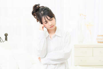 部屋で悩んでいるジェスチャーをする白いシャツを着た若い女性