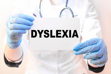 The doctor's blue - gloved hands show the word DYSLEXIA - . a gloved hand on a white background. Medical concept. the medicine