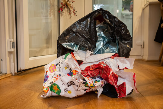 Christmas wrapping paper waste in a bin liner lying on a wooden floor