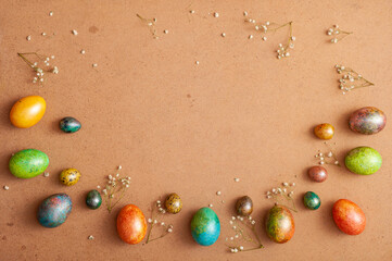 Happy Easter 2021. Colored painted eggs and small flowers on a brown cork background.