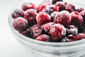Frozen cherries in a glass bowl on white background