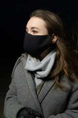 girl in a medical mask with a scarf on a black background