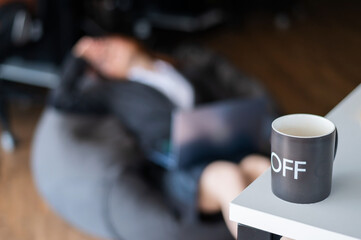 Business woman sleeping on a bean bag. Mug in the foreground.