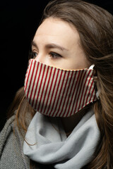 girl in a medical mask with a scarf on a black background