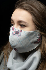 girl in a medical mask with a scarf on a black background