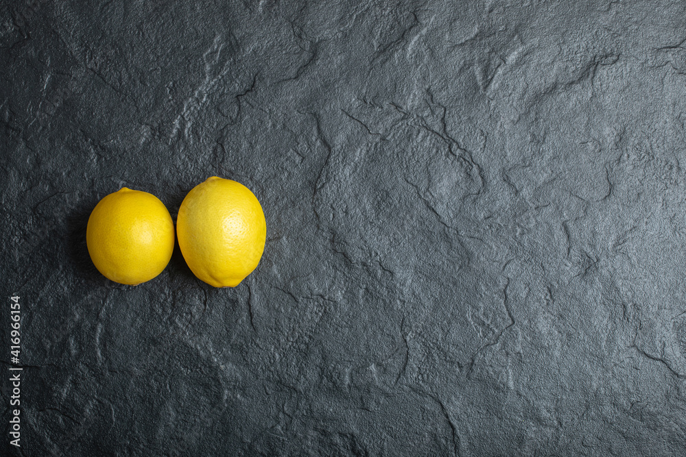 Wall mural wide angle photo of two fresh lemon on black background