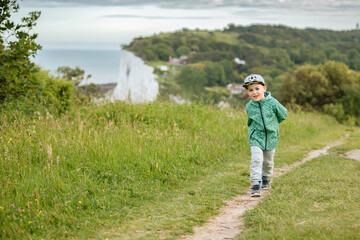 Little boy runs along a path by the sea. Sea in England. Big white cliffs by the sea 