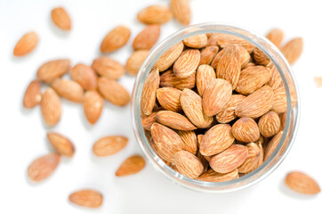 Top view of dry almond seeds in glass bowl on white background ready for cooking