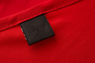 Blank black laundry care clothes label on red fabric texture background