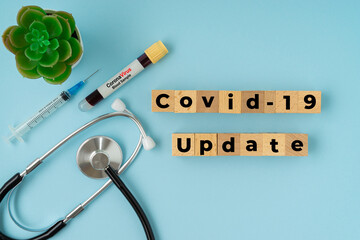 COVID-19 UPDATE text with syringe, stethoscope and blood sample vacuum tube on blue background....