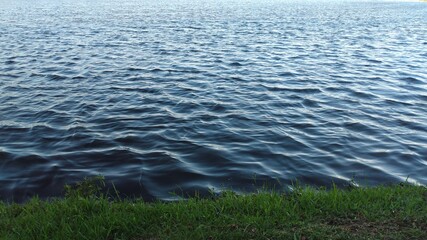 The calm waters of the lake reflect the blue of the sky and the small green lawn places the viewer in this beautiful image.