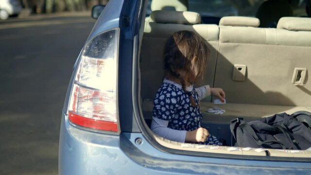 Happy little girl playing with learning cards in the back of a vehicle