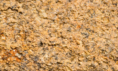 Granular structure of yellow-gray granite rock close-up.