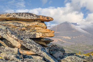 Slabs of granite rock against the backdrop of mountains and blue sky.