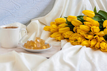Fototapeta na wymiar A bouquet of fresh yellow tulips and breakfast with coffee and homemade marmalade. Breakfast in bed. Spring flowers. The concept of spring and holiday, March 8, International Women's Day,