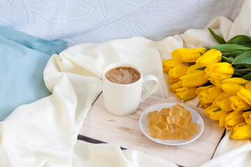 Fototapeta na wymiar A bouquet of fresh yellow tulips and breakfast with coffee and homemade marmalade. Breakfast in bed. Spring flowers. The concept of spring and holiday, March 8, International Women's Day,