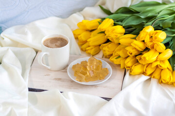 A bouquet of fresh yellow tulips and breakfast with coffee and homemade marmalade. Breakfast in...
