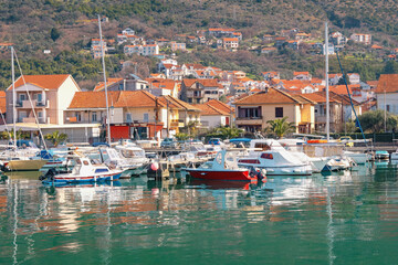 Mediterranean town at foot of mountain, fishing boats in harbor. Montenegro, Adriatic Sea. Marina Kalimanj in Tivat city