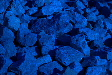 A pile of rocks with shadows from the latter day sun, and tinted overall blue.