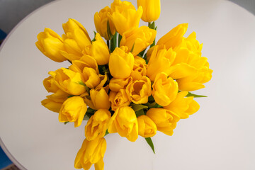 A bouquet of fresh yellow tulips. Bouquet of tulips on the table, top view. Spring flowers in the interior. The concept of spring or holiday, March 8, International Women's Day,