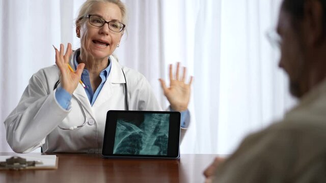 Doctor is shows X-ray images to patient on tablet pc computer. Slow motion concept of doctor discuss personal healthcare.