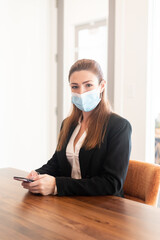Pretty young business woman wearing protective mask. 