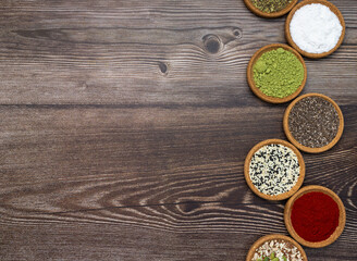 Wooden flat lay with different types of basic spices and herbs, background for gastronomy and cookery. Copy space, top view.