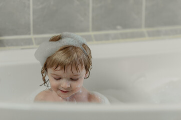 little smiling child sits in a large bubble bath. View from above. Flatley