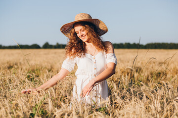 Girl with long curly hair poses in a wheat field