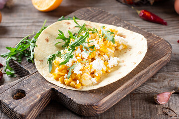 Birria tacos with egg, corn, cheese and vegetables on a table