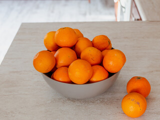 Fresh oranges in a bowl on a marble table. Seasonal fruit. Healthy lifestyle. Vegan food
