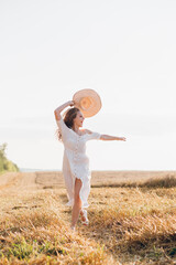 Girl with long curly hair poses in a wheat field
