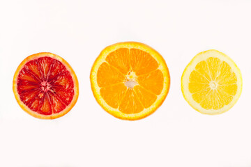 3 citrus slices against a white background: blood red, orange and lemon yellow