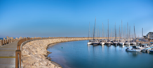 Landscape of  Herzliya Marina with sailing yachts and  pass way to  light house.