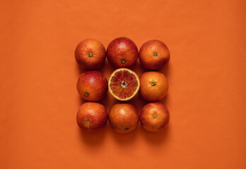 Fresh blood  whole and half oranges on a orange  background. Seasonal citrus fruit.Top view with copy space.