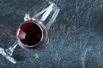 A glass of wine and empty glass on the dark background