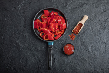 Pan of sliced red bell peppers with ground pepper and ketchup