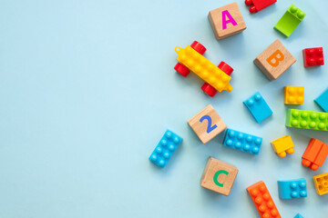 Top view of colorful bricks with toys on blue table background. Figures and alphabet signs. Education concept